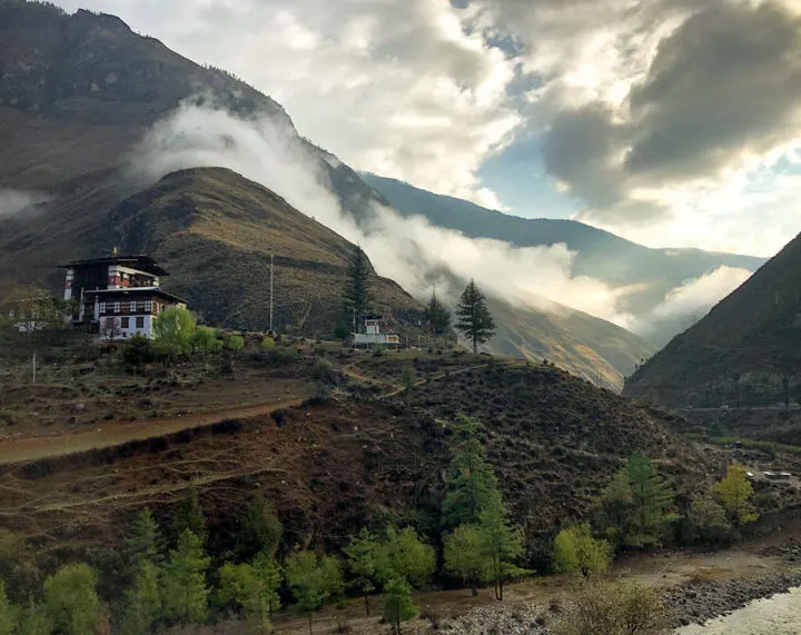 Clouds drifting through a forested mountain valley in Bhutan