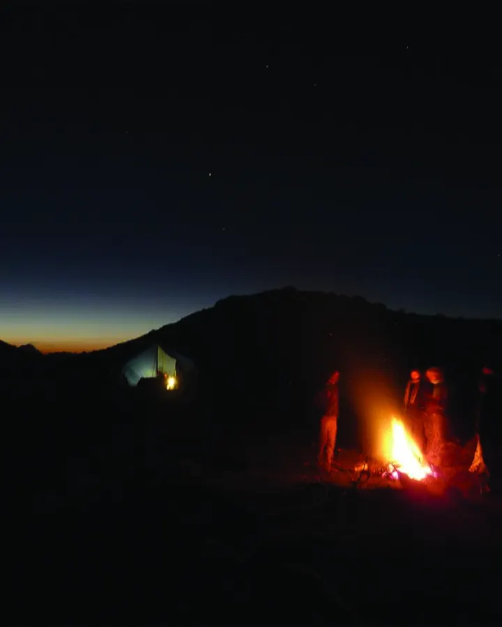 Campfire glowing under the night sky at a mountain campsite